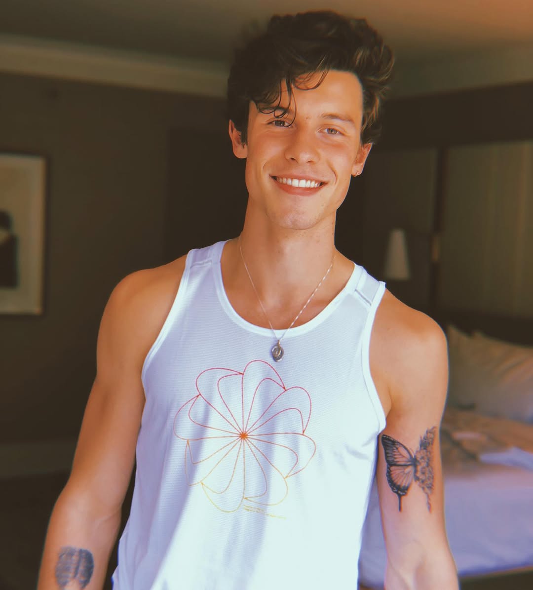 Shawn Mendes showing the completed black butterfly and floral tattoo on his left upper arm