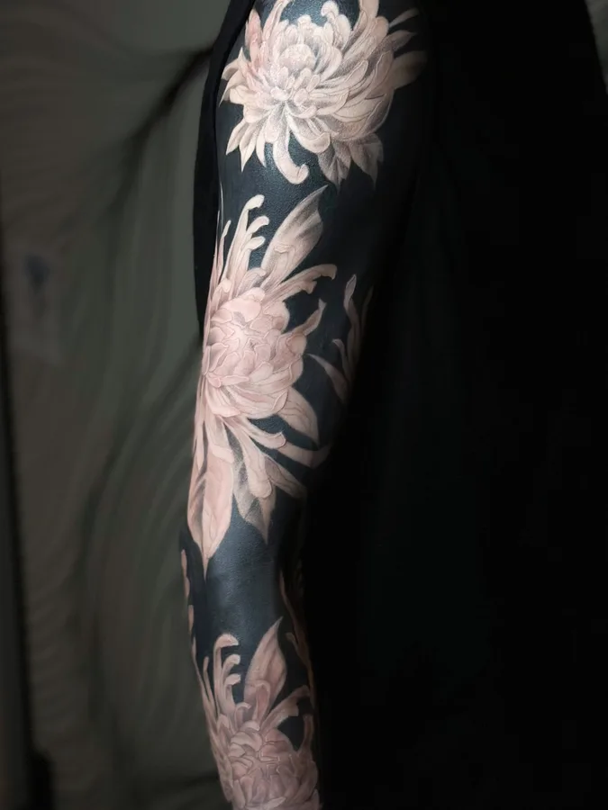 YURAの黒で塗りつぶした背景に菊を描いたタトゥー（腕）