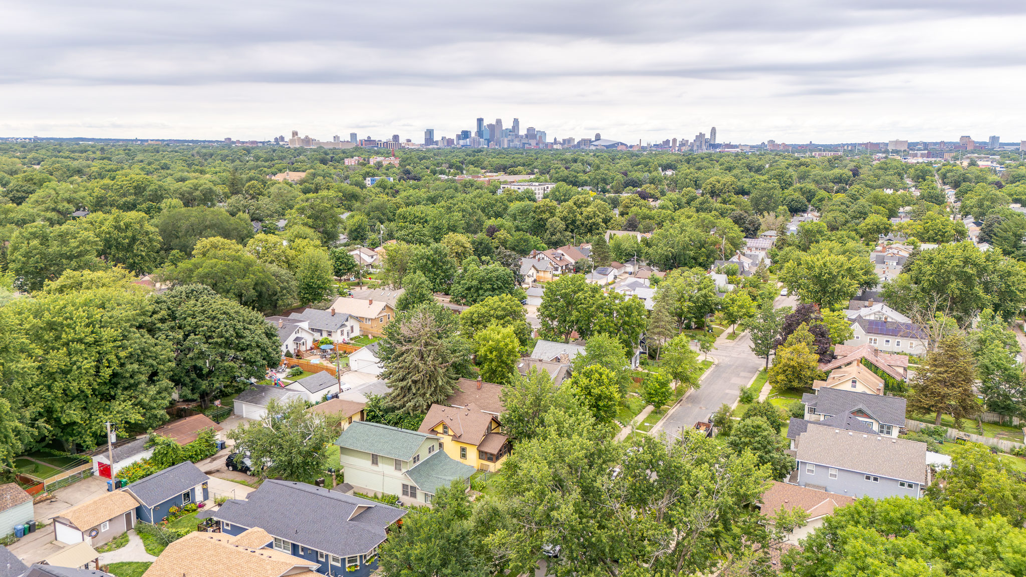 Aerial view over a Twin Cities neighborhood with the Minneapolis skyline on the horizon