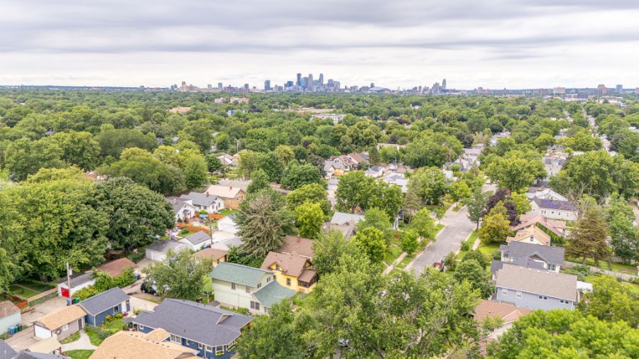 Aerial view over a Twin Cities neighborhood with the Minneapolis skyline on the horizon