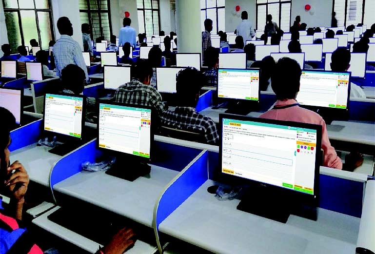 Candidates taking a computer-based exam at an SSC examination center with individual PCs and invigilators monitoring