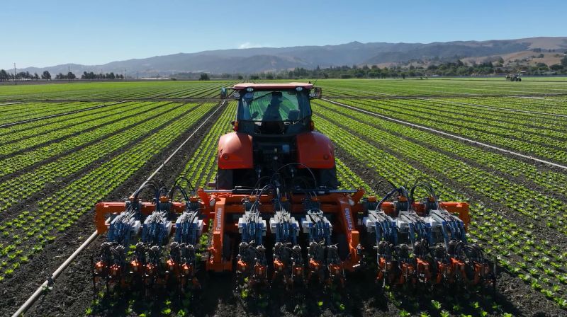 A modern tractor with robotic arms in a field