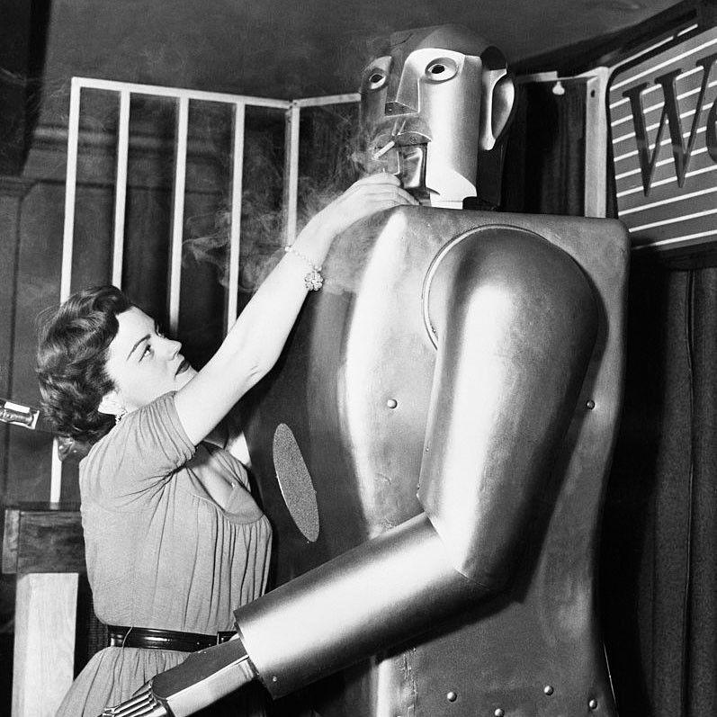 Jeanne Dowling se estira para encender un cigarrillo a Elektro, un robot de más de dos metros de altura construido por Westinghouse.