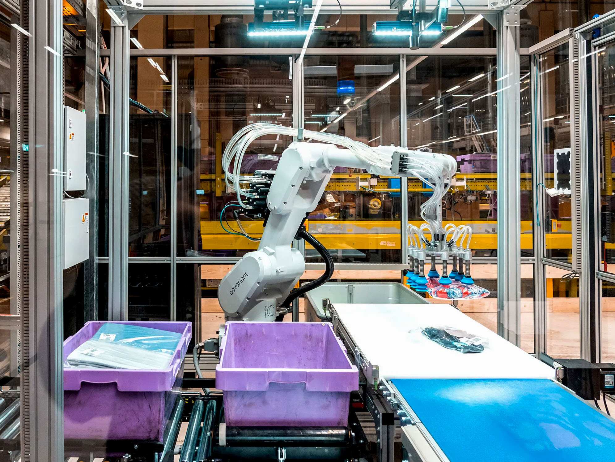 un brazo robótico de almacén levanta un objeto con muchas ventosas para colocarlo en un contenedor