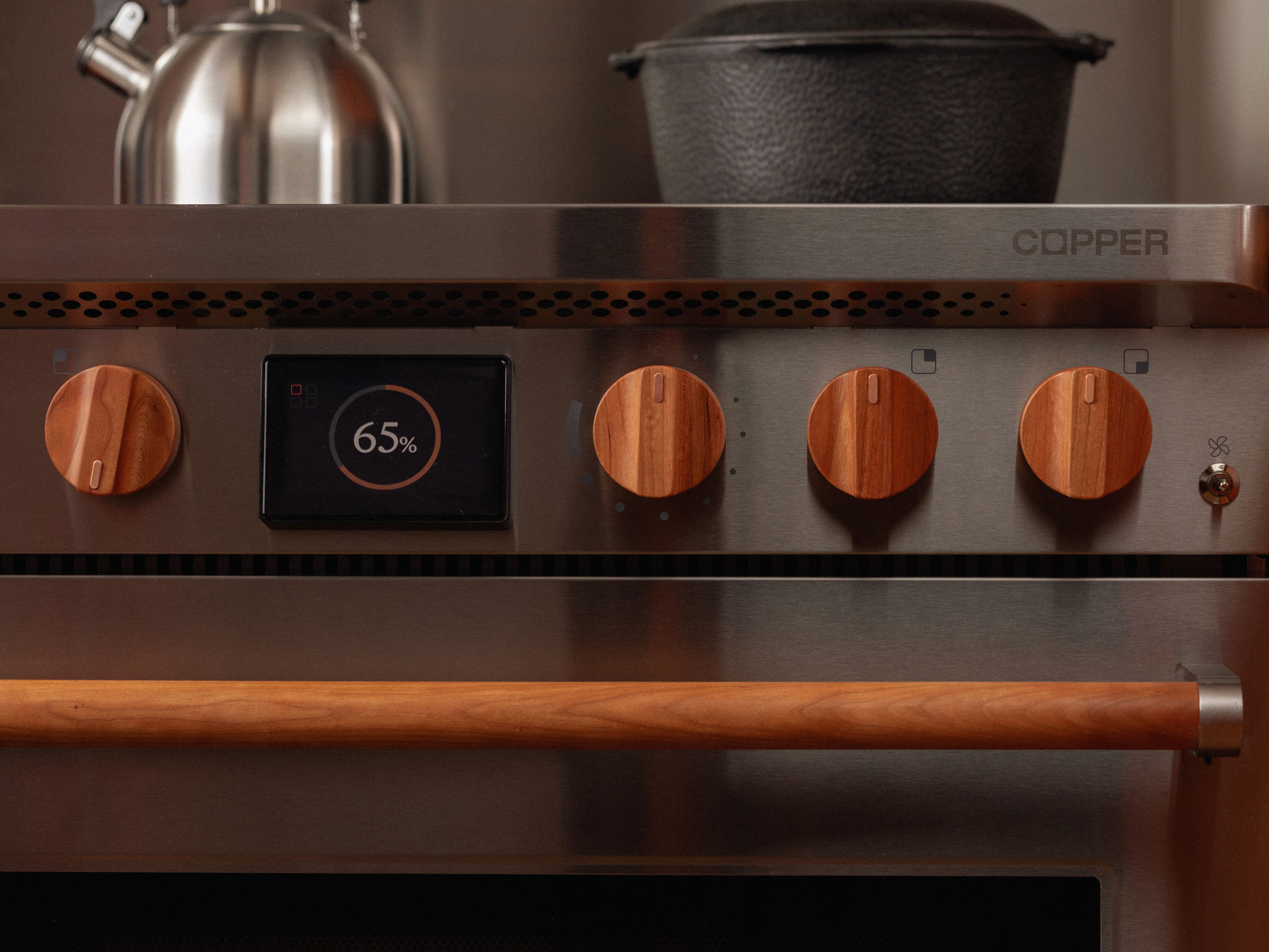 primer plano de una cocina de acero inoxidable con mandos con acabado en madera y una pantalla en la que se lee «65 %»