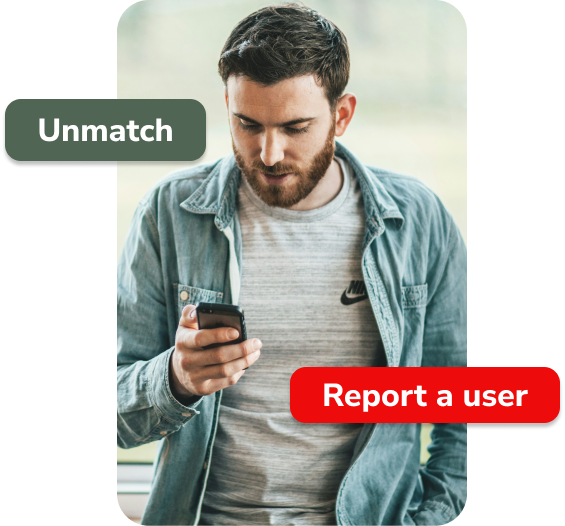 Image of man holding a phone with an unmatch and report a user button displayed on top