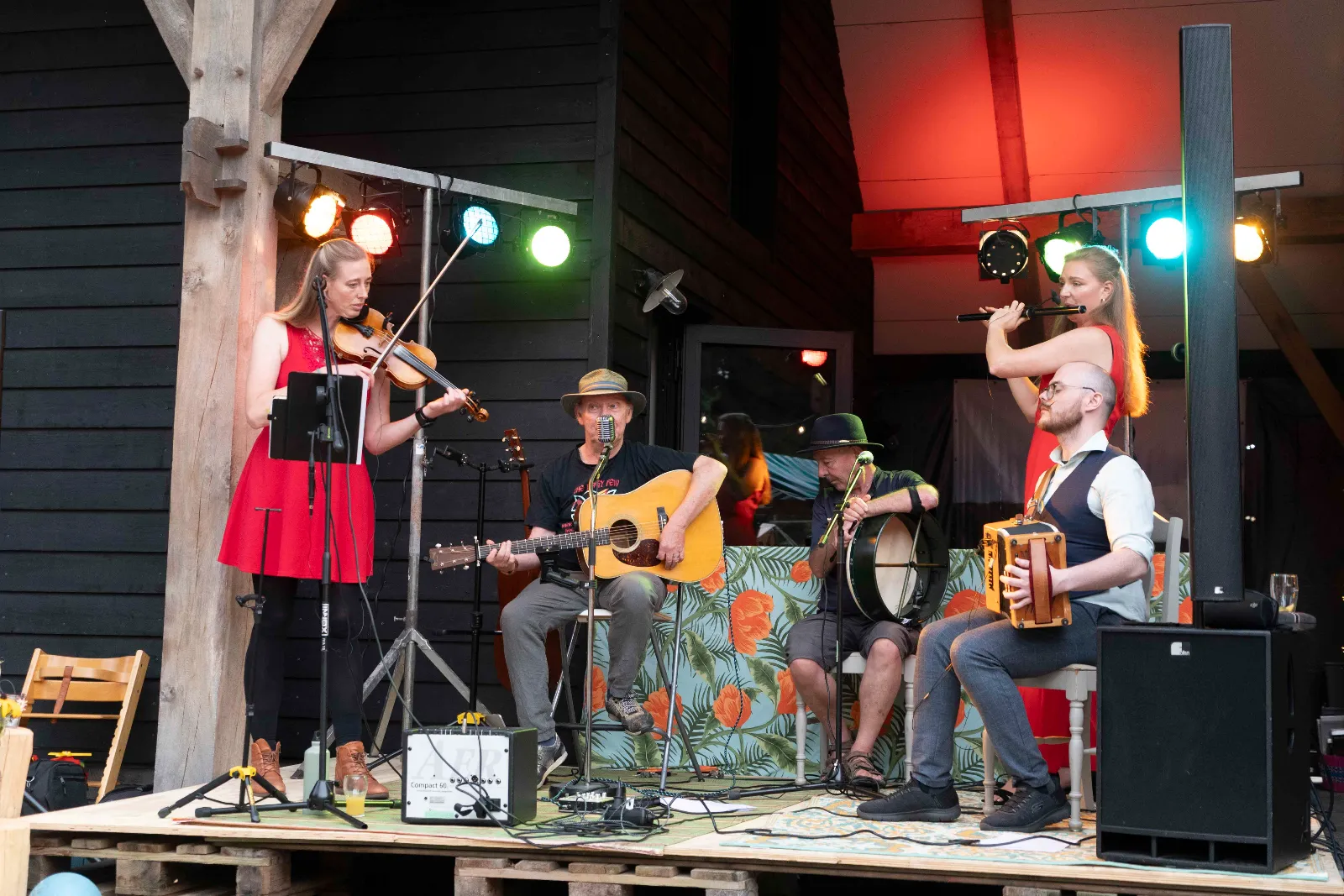De band op een podium van pallets: viool, gitaar, bodhrán en box