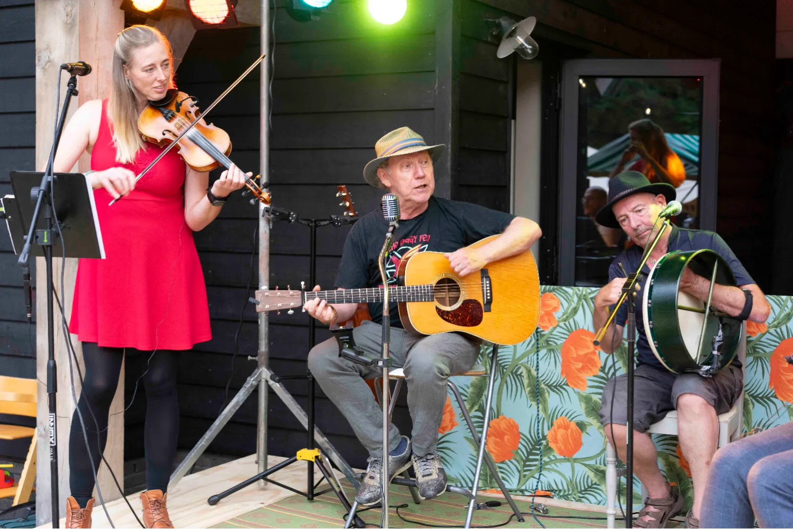 Violiste en gitarist spelen samen op een klein podium onder de bomen