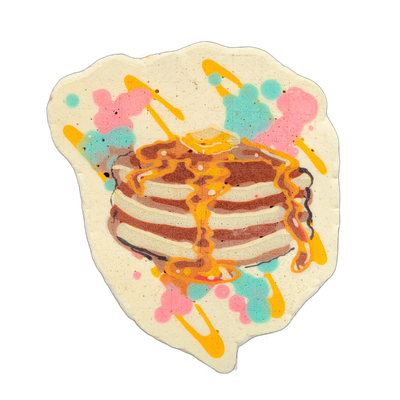A stack of three pancakes with a pat of butter on top and syrup dripping down the sides, surrounded by splashes of pink, teal, and orange batter on a cream-colored background shaped like a rough oval. Rendered in pancake art with bold brown outlines and layered batter fills, using a cream-to-brown…