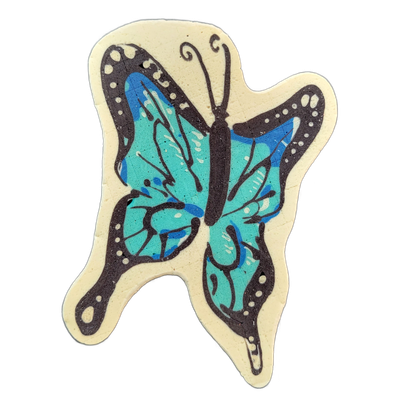 Pancake art of a butterfly with open wings, rendered in teal and blue with a dark brown-black body and wing borders, set against a cream-colored background silhouette with a scalloped edge. Bold black outlines define the wing shapes and internal vein-like markings, with small dot accents along the…