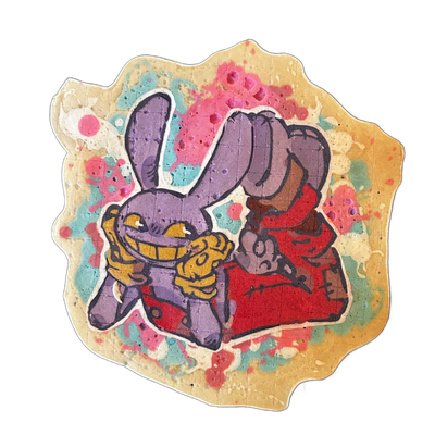 Pancake art depicting a cartoon rabbit character named Jax rendered in violet and purple tones, wearing a red outfit, with an exaggerated wide grin showing golden-yellow teeth, one large fist raised and one arm extended forward, set against a background of pink, teal, and yellow paint-splatter shap…