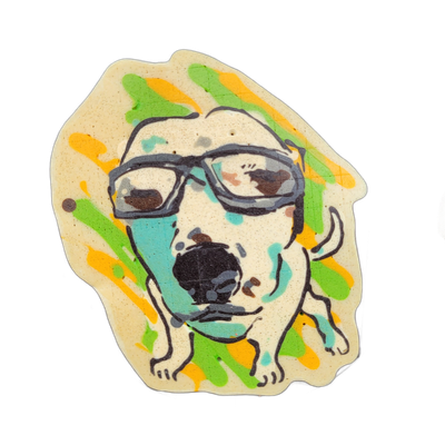 A pancake art piece depicting a cartoon-style dog face with a wide-open mouth and large dark nose, wearing thick-framed rectangular glasses, with its front paws visible below the face. Bold black outlines define the figure against a light cream-colored base, with streaks of green, orange, and teal…