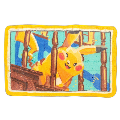 Pancake art depicting Pikachu, the yellow mouse Pokémon character, shown from a low angle as it leans forward between vertical wooden chair or fence spindles against a teal and blue background, with a brown wooden structure visible in the lower left corner — the composition appears to reference Van…