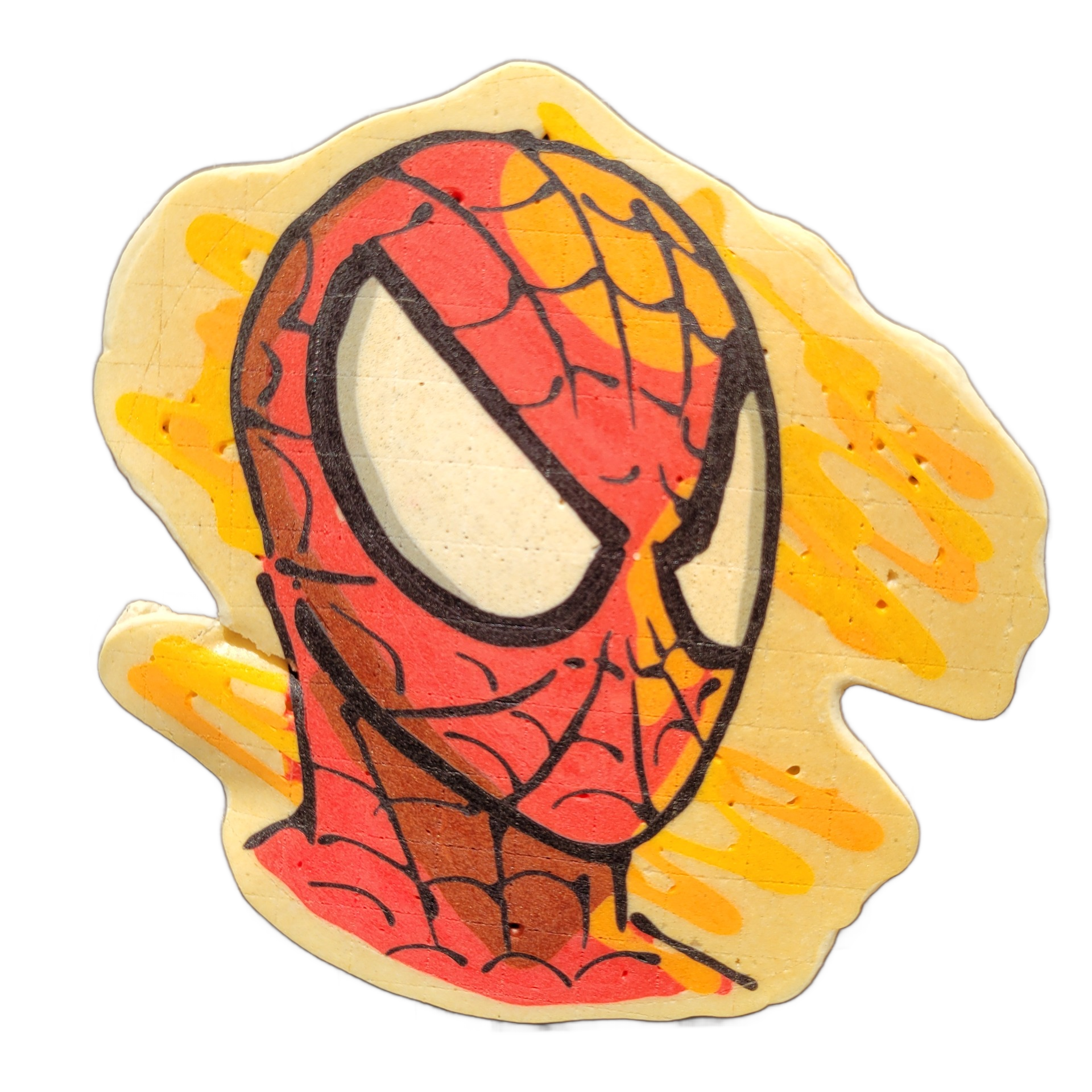 A pancake art piece depicting a masked superhero face with large white oval eyes, a red and dark-red web-patterned mask covering the full head, and a loose splatter-style background in yellow and orange with drip-like edges. Bold black outlines define the web pattern and eye shapes, with red and or…