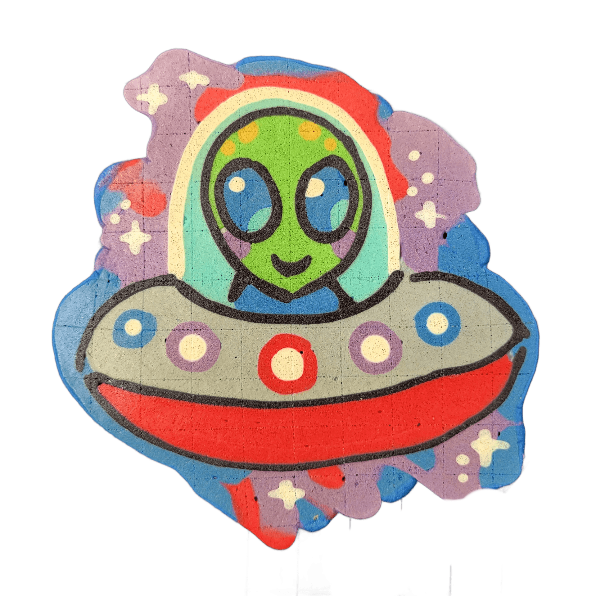 Pancake art depicting Trav, a green-skinned cartoon alien with large dark oval eyes and a small curved mouth, shown from the chest up inside a domed flying saucer cockpit with a rainbow-arched canopy; the saucer body is gray with a red underside and rows of circular lights in blue, purple, and whit…