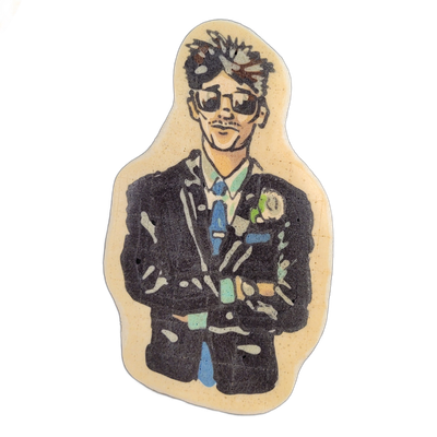 Pancake art of a figure named Grandson, depicted from roughly the waist up, wearing a dark suit jacket with a blue tie, a light-colored dress shirt, and a lapel detail, with arms crossed at the front; the face shows short, slightly tousled dark hair, sunglasses, and light stubble. Dan rendered this…