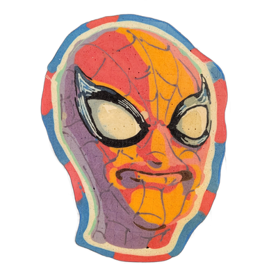 A pancake art portrait of a masked superhero face with large oval white eyes outlined in black, a subtle closed-mouth expression, and a web-line pattern drawn across the mask surface. Fine black squeeze-bottle lines form the web texture and eye outlines, with broad fills of red, orange-yellow, purp…