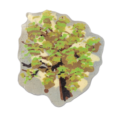 A pancake art piece depicting a single tree with a dark brown trunk and spreading branches visible through the canopy, rendered in a top-down or slightly elevated perspective. The foliage is applied in layered patches of bright green, olive, and tan batter over a pale cream background, with bold ir…