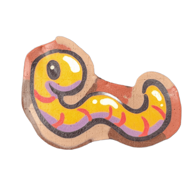 Pancake art depicting Hermie the Wurmy, a worm character from the JoP cast, shown in a loose S-curve body shape with a rounded head on the left side, a small dot eye with a white highlight, a curved open mouth rendered in purple, and a body that tapers and curls to the right; the surrounding area i…