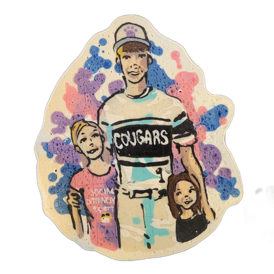 Pancake art depicting three children: a taller child in the center wearing a cap and a jersey with 'COUGARS' printed across the chest, flanked by a shorter child on the left in a pink shirt with small text reading 'Social Distancing Expert' and a smaller child on the right in a dark shirt with one…