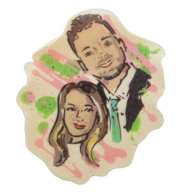 Pancake art portrait of two people: a man positioned behind and above, with short curly brown hair, light stubble, and a dark suit jacket with a white shirt and teal tie; a woman positioned in front, with long brown and blonde hair, wearing a white top, both facing forward. Rendered by Dan with bol…