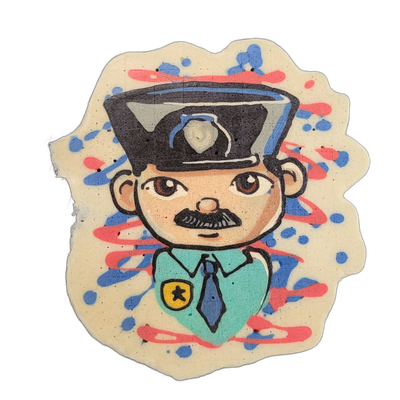 Pancake art depicting a cartoon-style figure wearing a dark peaked cap with a badge on the front, a teal uniform shirt with a gold and black star badge on the chest, and a dark tie, with a round face, small mustache, and brown eyes looking forward. Bold black outlines define the figure against a cr…