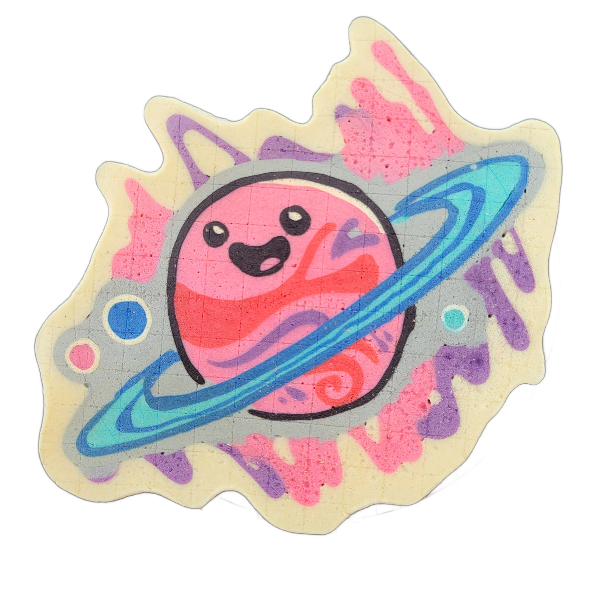 Pancake art depicting Saturnina (Nina), an original JoP character designed as a cartoon planet with a round pink body, two dot eyes, and an open smiling mouth, encircled by a blue and teal orbital ring rendered in bold, layered outlines; two small orbiting bodies — one blue and one teal — appear at…