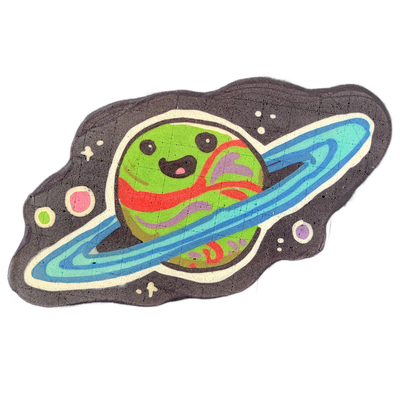 Saturnina, a JoP original character depicted as a round planet with a cartoon face — two dot eyes, a small open mouth, and a pink tongue — surrounded by blue concentric rings and set against a dark space background with small scattered circles suggesting stars and other planets. The pancake art use…