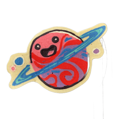 Saturnina, a JoP original character depicted as a round planet with a cartoon face — two small circular eyes and an open mouth with a black outline — encircled by a diagonal ring, with two small moon-like circles flanking the planet body. The pancake art uses bold black outlines, a red and violet s…