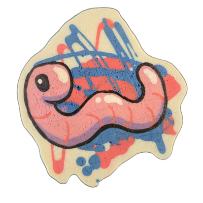 Pancake art depicting Hermie the Wurmy, a worm character from the JoP cast, shown as a simplified cartoonish worm shape with a round head, small circular eye with a white highlight, a slight curved mouth, and a segmented body that curves in an S-shape. Drawn by Dan with bold black outlines and fill…