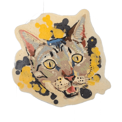 Pancake art portrait of a cat named B'Yonce, shown from the shoulders up, facing slightly left, with yellow-irised eyes, striped tabby markings, a pink open mouth, and prominent whisker dots. The portrait is rendered with bold black outlines and filled with muted brown, gray, blue, red, and green b…