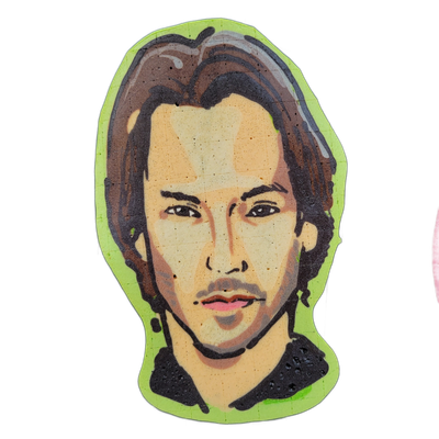 Pancake art portrait of a young man with shoulder-length dark brown hair swept back, defined dark eyebrows, light stubble, and slightly parted lips, set against a bright neon green background cutout shape. Rendered with bold black outlines and broad batter fills in warm peach and tan skin tones, br…
