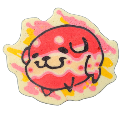 Pancake art depicting Poffridge, a Shiba Inu-shaped sentient poffertje from the JoP cast, rendered as a round, slightly flattened face with small paws visible at the bottom, a wide blunt nose, and two upward-curved brow marks above closed or squinting eyes, set against a cream-colored spiked splatt…