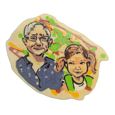 Pancake art depicting two figures labeled Garry and Carter: an adult with short gray hair, glasses, and a blue shirt standing beside a child with brown hair pulled back, wearing a green and white top, both facing forward and appearing to smile. The piece uses bold black outlines with filled color a…