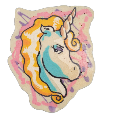 A unicorn head in profile facing right, with a spiral horn, flowing mane rendered in orange and yellow, teal color covering the neck and lower face area, and a light-colored face with a defined eye and small nostril; the background of the pancake art piece shows pink and purple paint-splash shapes…