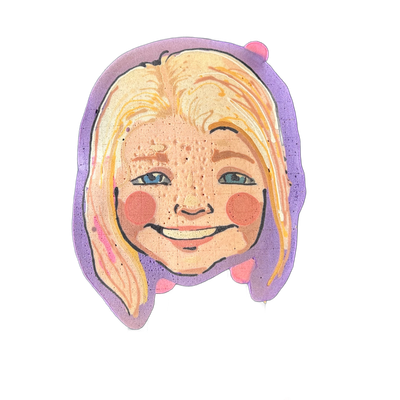 A pancake art portrait of a smiling face with shoulder-length blonde hair, blue eyes, rosy circular cheeks, freckles across the nose and cheeks, and pink lips showing teeth, set against a purple background layer that extends around the face like a halo or border. Wella rendered the piece with bold…
