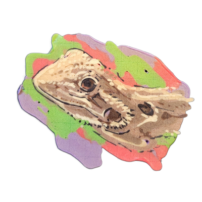 Pancake art portrait of Bowser Peaches Heaney, a bearded dragon, depicted in a close-up head-and-shoulders view facing left with the mouth slightly open, one eye visible, and textured scales rendered across the face and jaw. Fine black outlines define the facial features and scale patterns, with cr…