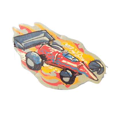 A stylized race car with an open cockpit and large exposed wheels, shown at a three-quarter angle and surrounded by flames rendered in red, orange, and yellow, with the car body filled in red and blue-gray tones and bold black outlines separating all major shapes. The pancake art uses thick squeeze…