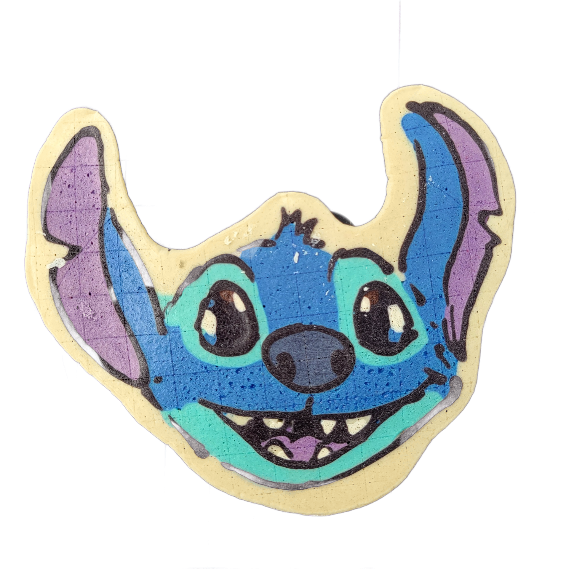 A pancake art piece depicting Stitch, the blue alien creature from Disney's Lilo & Stitch, shown as a close-up face with large brown eyes, a wide open mouth showing small pointed teeth and a pink tongue, a broad dark nose, and two tall rounded ears with purple inner coloring that extend upward and…