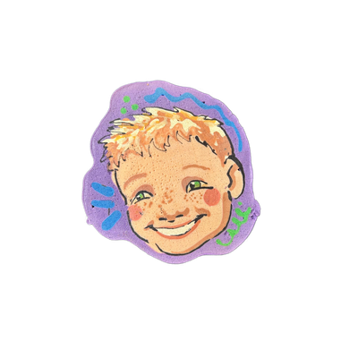 Pancake art portrait of a child's face named Wally, featuring short strawberry-blond hair, green eyes, freckles across the nose and cheeks, rosy cheeks, and a wide open-mouth smile, set against a purple blob-shaped background decorated with blue wavy lines, blue brushstroke shapes, green dots, and…