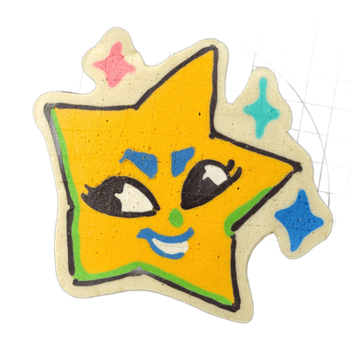 Pancake art depicting Charli, a star-shaped original character from the JoP cast, rendered as a five-pointed star with a cartoon face featuring heavy-lidded eyes with lashes, blue angular marks beneath each eye, a small green nose dot, and a blue-outlined smile with white teeth, surrounded by a gre…