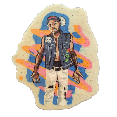 Pancake art depicting a young man standing in a relaxed pose, wearing a denim sleeveless vest open over a bare chest, white distressed pants, a belt, and a cap with what appears to be sunglasses resting on the brim; his arms hang at his sides with fingers loosely spread, and a small floral detail a…