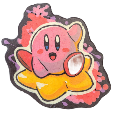 Pancake art depicting Kirby, the round pink Nintendo video game character, shown from the front with arms outstretched, an open mouth, rosy cheeks, and small oval eyes with white highlights, wearing or emerging from a yellow star shape at the bottom. Bold black outlines define the figure against a…