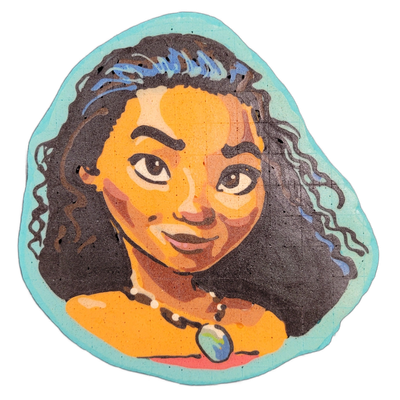 Pancake art depicting Moana, the Disney animated character, shown as a close-up portrait of a young Polynesian girl with long dark curly hair, warm brown skin, large dark eyes, and a blue-green pendant necklace against bare shoulders. Dan rendered the piece with bold black outlines, warm orange and…