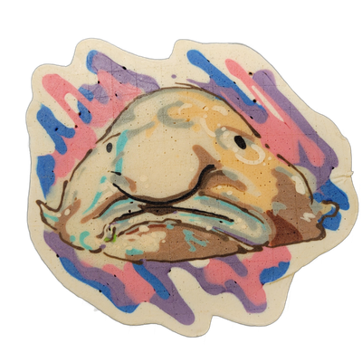 A blobfish rendered in pancake art, shown face-on with a large rounded head, drooping fleshy nose, small dark eyes, and a downturned mouth, resting on a broad lower body mass. Fine dark brown outlines define the facial features and form, filled with cream, tan, and muted brown batter tones, set aga…