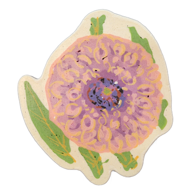 A large stylized flower rendered in pancake art, shown face-on with a dense cluster of petals radiating outward from a small, multicolored center that includes areas of blue, brown, black, green, and white; several green leaves with yellow vein lines appear around the lower and upper edges of the b…