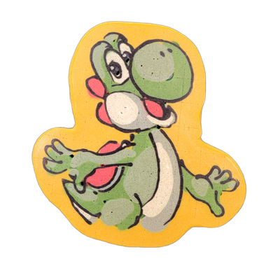 Pancake art depicting Yoshi, the green dinosaur-like character from Nintendo's Mario franchise, shown in a jumping or running pose with both arms outstretched, legs bent, mouth open, and large expressive eyes looking upward and to the left. The piece uses bold black outlines with filled areas of gr…