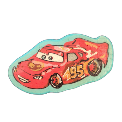 A pancake art depiction of Lightning McQueen, the red racing car character from Pixar's Cars, shown in a three-quarter front view with the number 95 on the side, animated eyes on the windshield, and a open-mouthed grille expression, set against a teal/turquoise oval background border. Dan rendered…