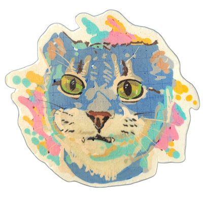 Layla is a cat depicted face-on, with green eyes, a light-colored muzzle, brown nose, and tabby-style stripe markings rendered in blue-gray tones against a blue background. The pancake art uses fine dark outlines for facial features and whiskers, broader fills for the blue face and background, and…