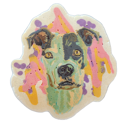 Pancake art depicting the head and upper neck of a dog, facing forward, with floppy ears, yellow-amber eyes, a dark nose, and a coat rendered in patches of gray-black, mint green, and tan. The portrait uses bold dark outlines with broad color fills in mint green, gray, and brown for the dog's face,…